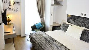 Hotellihuone, jossa on sänky, työpöytä, tuoli, lamppu ja taideteos seinällä.