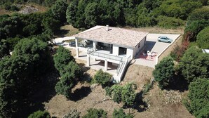Vue aérienne d’une maison moderne dotée d’un vaste patio, entourée d’une végétation luxuriante.