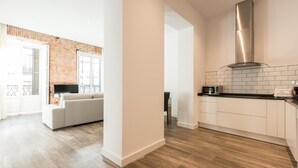 A modern apartment with a kitchen, a living area with a sofa, and a brick wall.