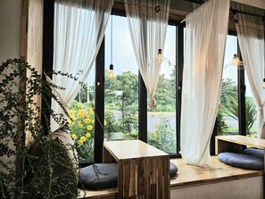 Una habitación con ventanas amplias, mesas de madera y lámparas colgantes.