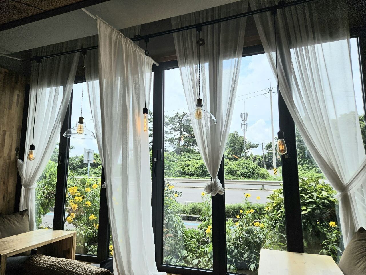 A room with large windows, white curtains, and hanging light fixtures.