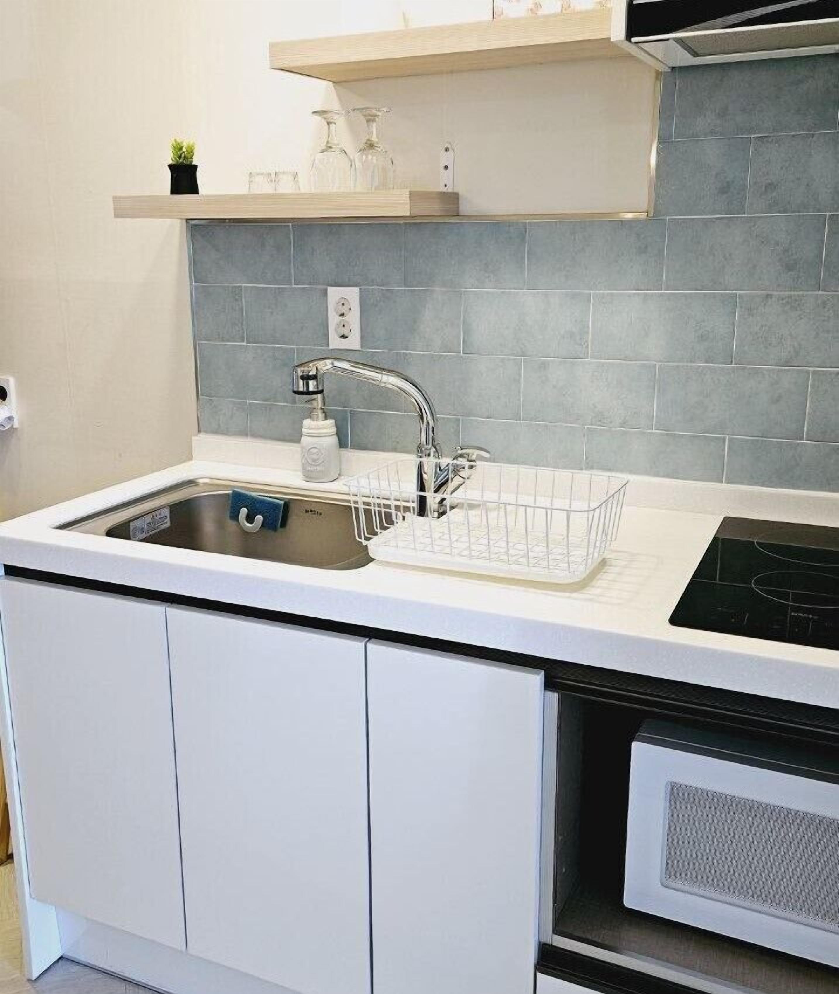 A modern kitchen with a stainless steel sink, a white countertop, and a built-in dishwasher.
