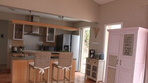 Eine Küche mit zwei Barhocker, einem Kühlschrank und einem Schrank mit Beschriftungen.