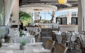 A restaurant with round tables, a bar area, and a large deer sculpture. - Sunseeker - Seagrove Home + Pools, Grill & Bikes! (Santa Rosa Beach)