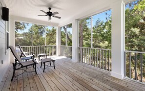 Eine überdachte Veranda mit Holzboden, weißen Geländern und einem Deckenventilator.