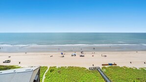 Ein Strand mit freiem Blick auf das Meer, wenigen Personen und einigen Strandsonnenschirmen.