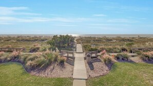 A wooden boardwalk leading to a beach with grassy dunes and benches. - Award-Winning Resort Amenities | Mariners Walk 4C (Isle of Palms)