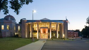 A modern building with a central glass facade, a dome structure to the left, and a flagpole on the right. - Crossroads Loft:  Steps from Rt. 66 & Carthage Square (Carthage)