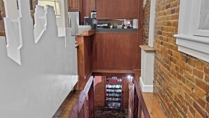 A staircase leading to a kitchen area with wooden cabinets and a brick wall. - Crossroads Loft:  Steps from Rt. 66 & Carthage Square (Carthage)