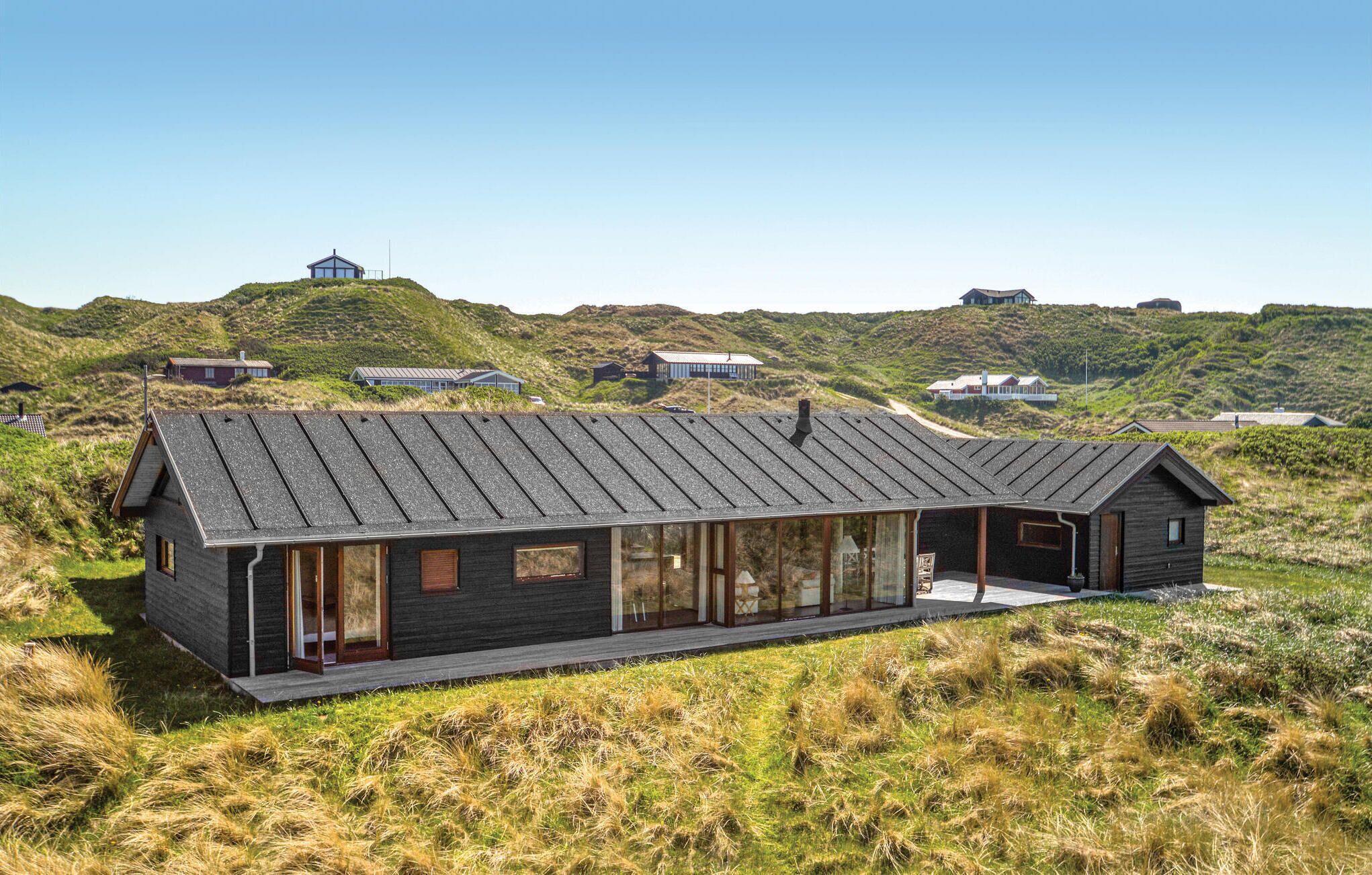 Ein modernes Haus mit Satteldach, großen Fenstern und Blick auf die umliegenden Hügel.