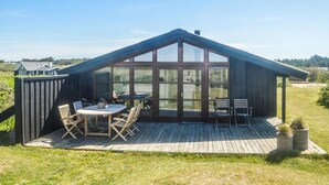 A wooden structure with a glass enclosure, a deck, and outdoor seating. - Gorgeous home in Løkken with kitchen (Løkken)