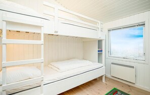 Ein Schlafraum mit Etagenbett, Fenster und Heizkörper.