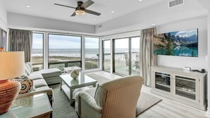 Een ruime woonkamer met een grote televisie, comfortabele zitplaatsen en een balkon met een prachtig uitzicht.