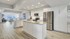Een moderne keuken met witte kastjes, roestvrijstalen apparatuur en een groot eiland.