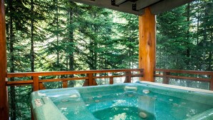 Un bain à remous sur une terrasse en bois, avec vue sur la forêt.