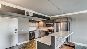 Een moderne keuken met roestvrijstalen apparatuur, een marmeren aanrechtblad en een ingebouwde oven.