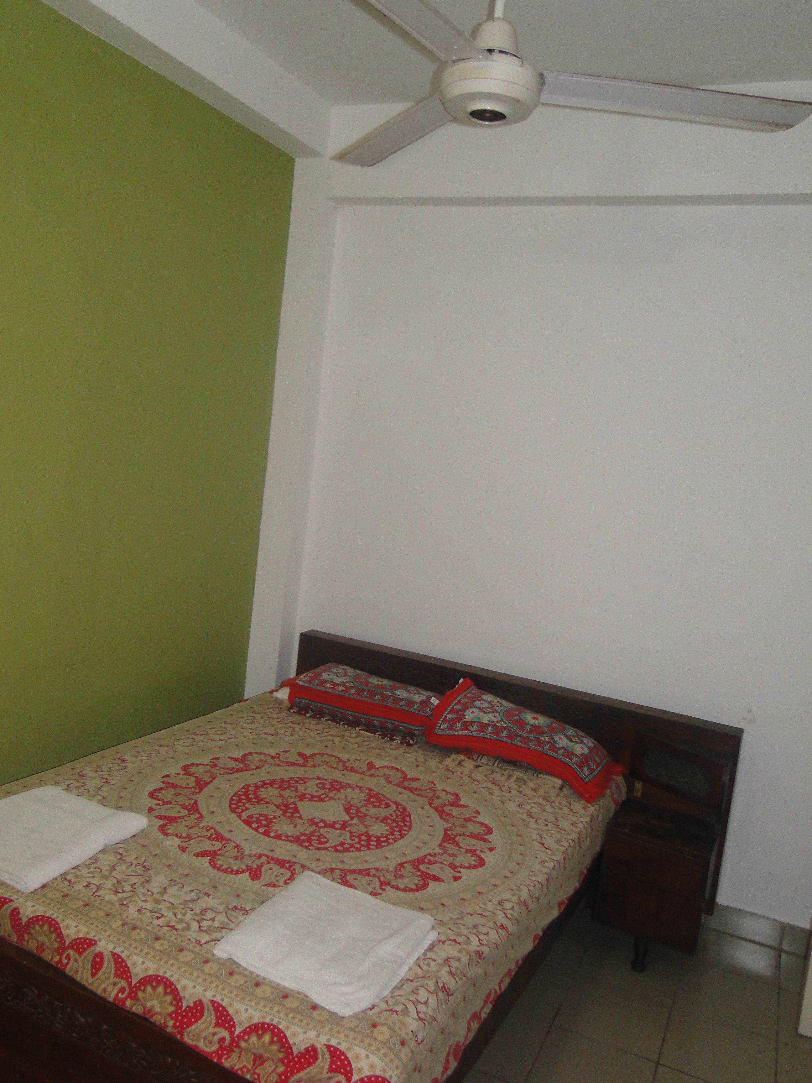 A bedroom with a bed, a ceiling fan, and a nightstand.