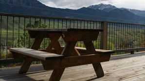 A wooden picnic table on a deck with a mountain view. - Yellowstone Archview Guesthouse- Stunning Views For Your Ultimate Family Getaway (Gardiner)
