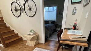 A modern kitchen with wooden flooring, a dining table, and a staircase leading to another room. - University Park Garden Guest House (Portland)
