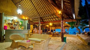 A beachside bar with wicker furniture, a thatched roof, and a view of the ocean. - Lumbung Bali Huts (Lembongan Island)