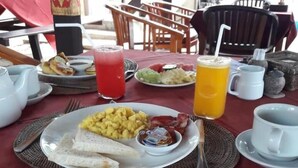 A breakfast table with plates of food, drinks, and utensils. - Lumbung Bali Huts (Lembongan Island)