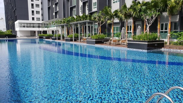 A modern hotel pool with clear blue water, surrounded by palm trees and lounge chairs.