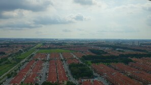Un quartiere residenziale caratterizzato da case con tetti rossi uniformi, aree verdi e una vista lontana sullo skyline della città.