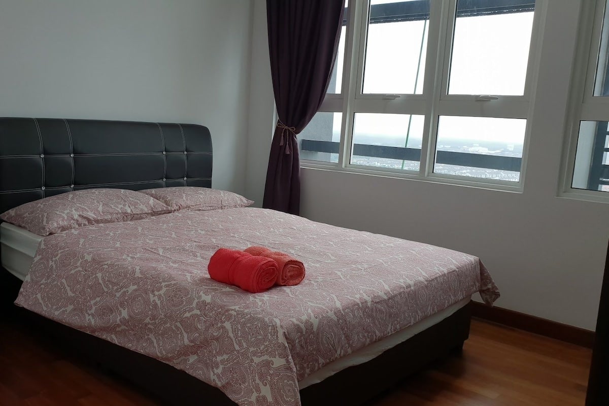 A bedroom with a bed, a nightstand, and a window with curtains.