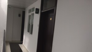 Ein Korridor mit schwarz-weißer Fliesenböden, einer hölzernen Bank, einer Tür mit Fenster und einem kleinen Schild an der Wand.