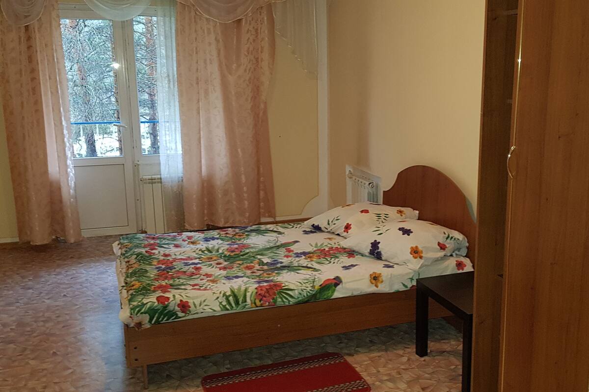 Une chambre à coucher avec un lit, une fenêtre avec des rideaux, une porte et un tableau au mur.