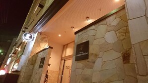A hotel entrance with stone facade, a sign indicating 'HOTEL TIMES-INN24', and a door labeled 'TUOL'. - Hotel Times-Inn24 Tsunashima (Yokohama)