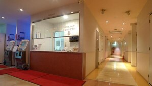 A hotel reception area with a check-out counter, self-service machines, and a red carpet leading to the entrance. - Hotel Times-Inn24 Tsunashima (Yokohama)