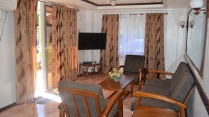 A living room with a sofa, two armchairs, a coffee table, and a flat-screen TV.