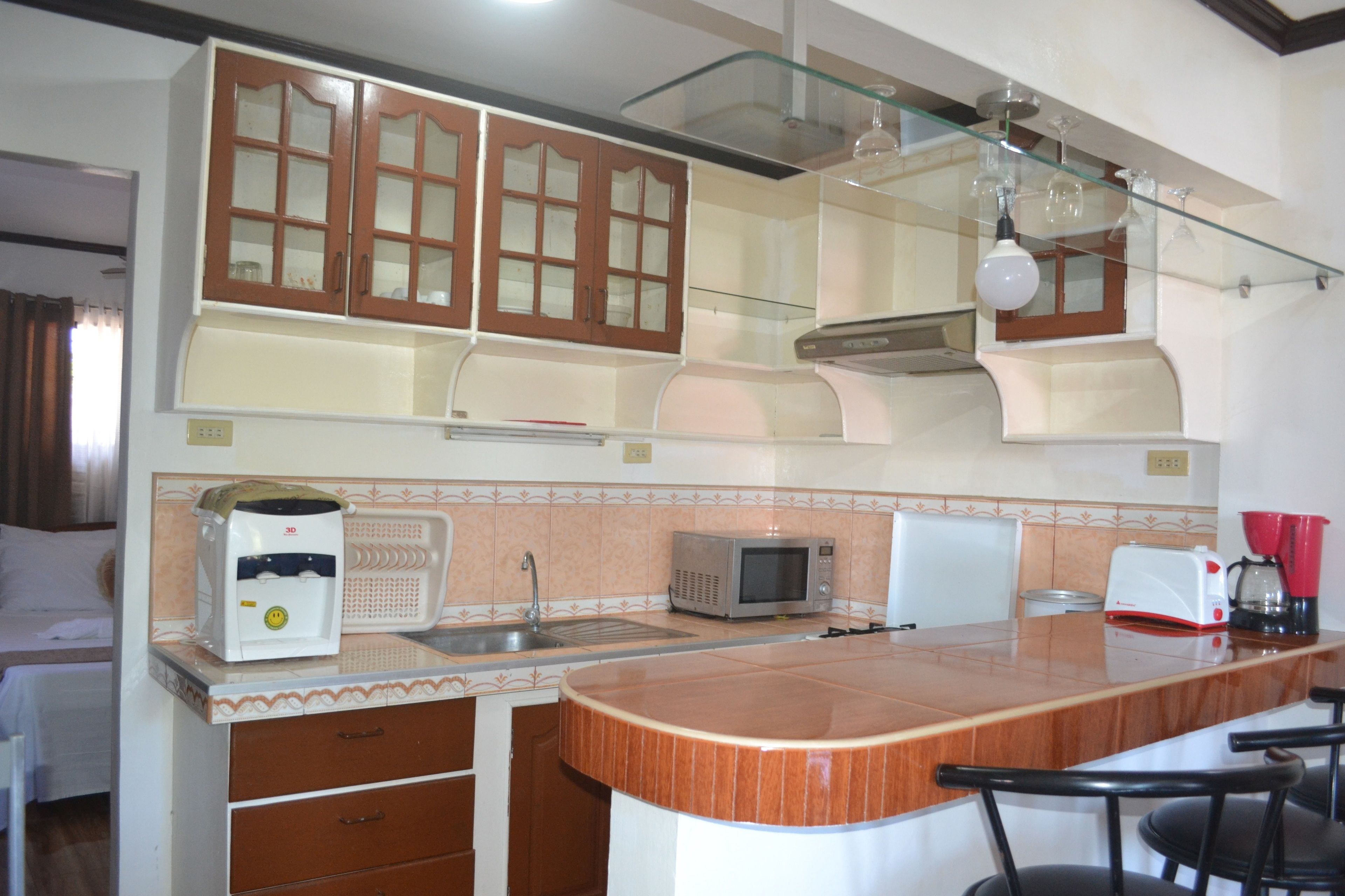 A compact kitchen with wooden cabinets, a microwave, a coffee maker, and a sink.