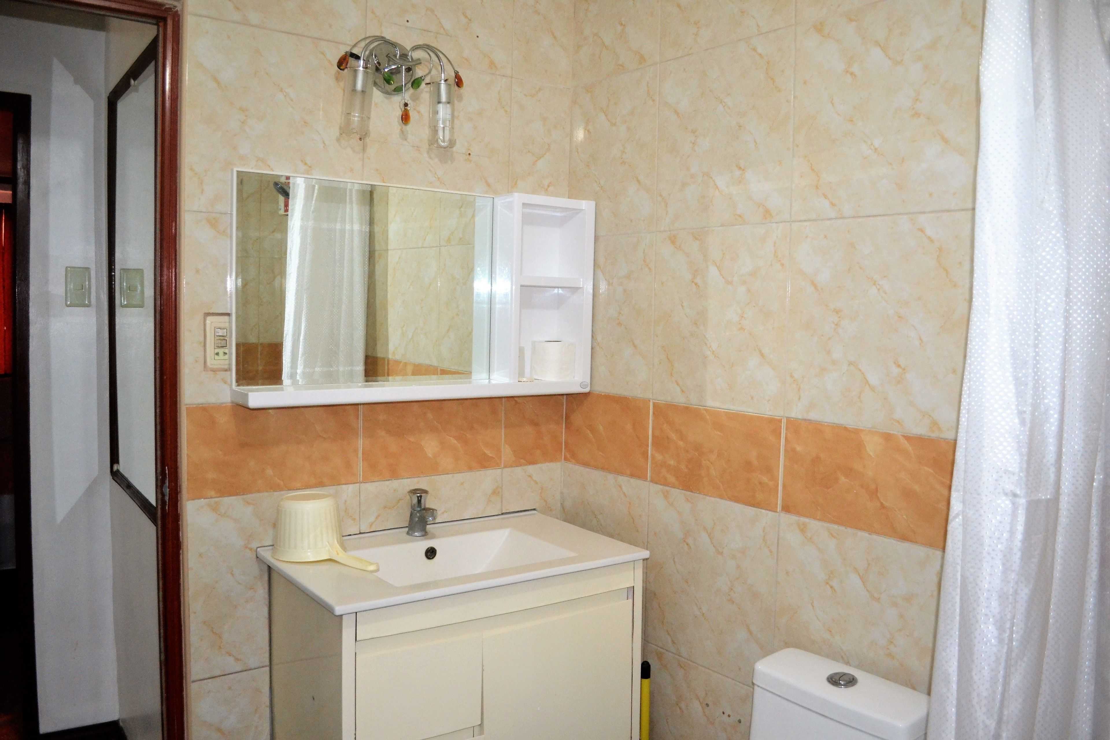 A bathroom with a sink, mirror, and toilet.