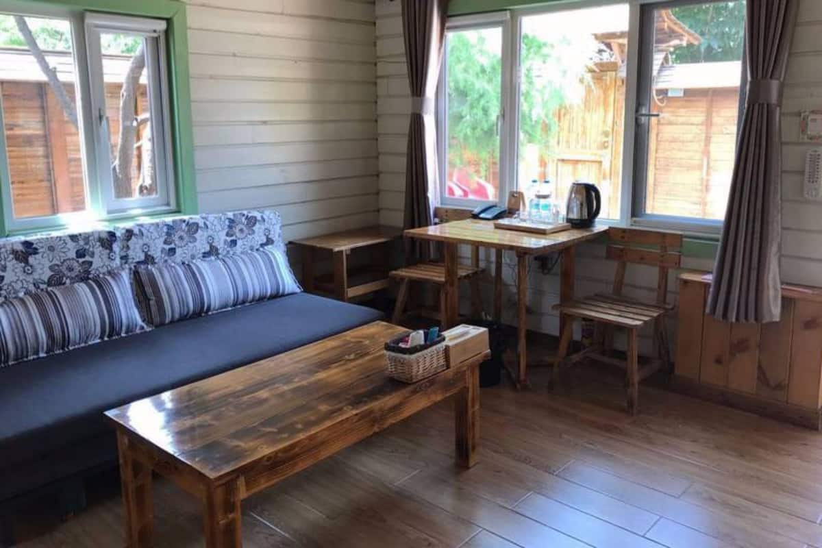 A cozy cabin interior with a wooden sofa, a dining table, and chairs.