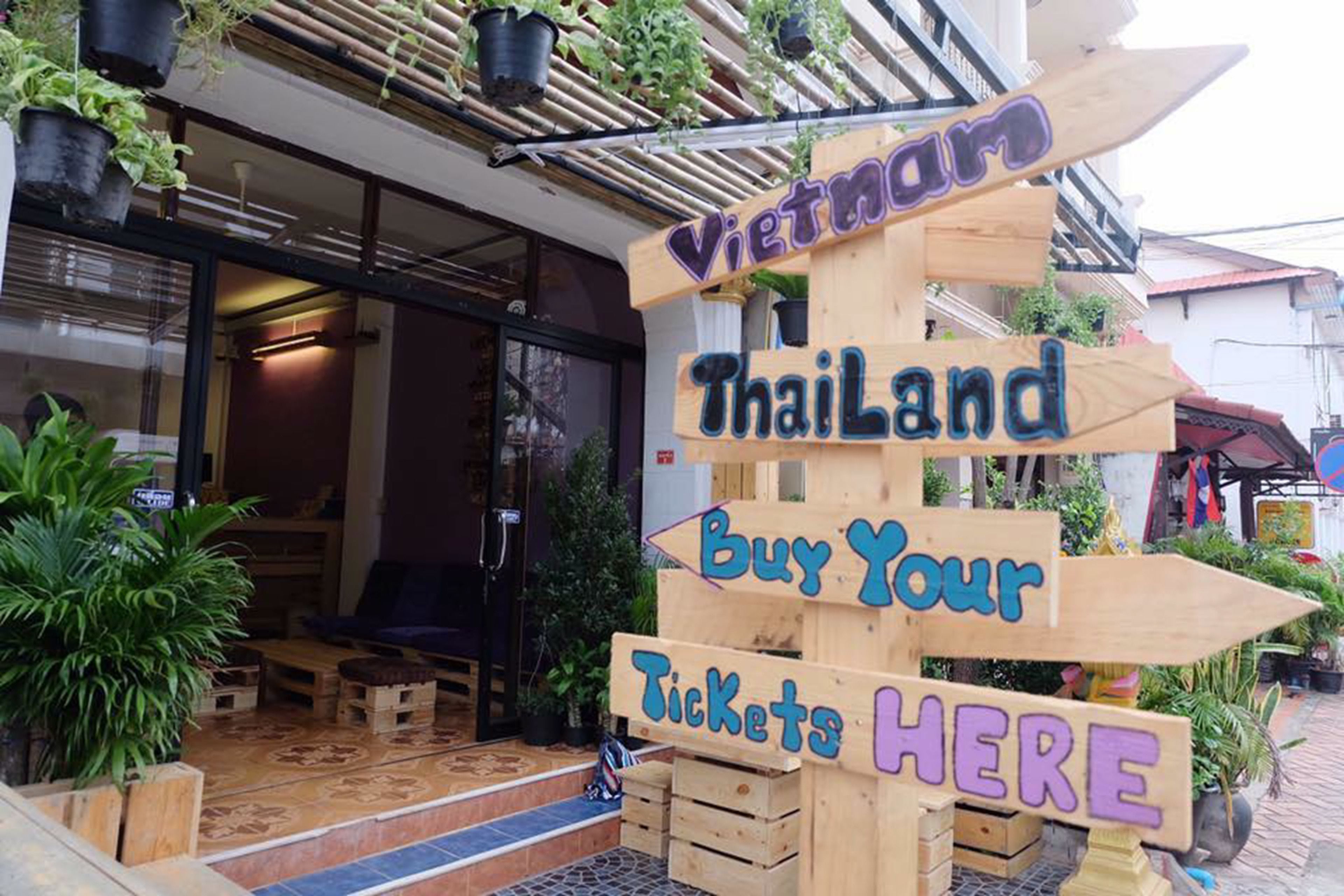 A wooden sign with arrows pointing to different destinations, including Vietnam and Thailand, and a sign that says "Buy Your Tickets Here".
