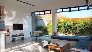 A modern living room with a TV, a coffee machine, a dining table, and a sofa. - Fabia Villas (Seminyak)