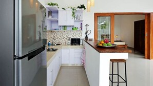 A modern kitchen with white cabinets, a built-in stove, and a wooden countertop. - Fabia Villas (Seminyak)