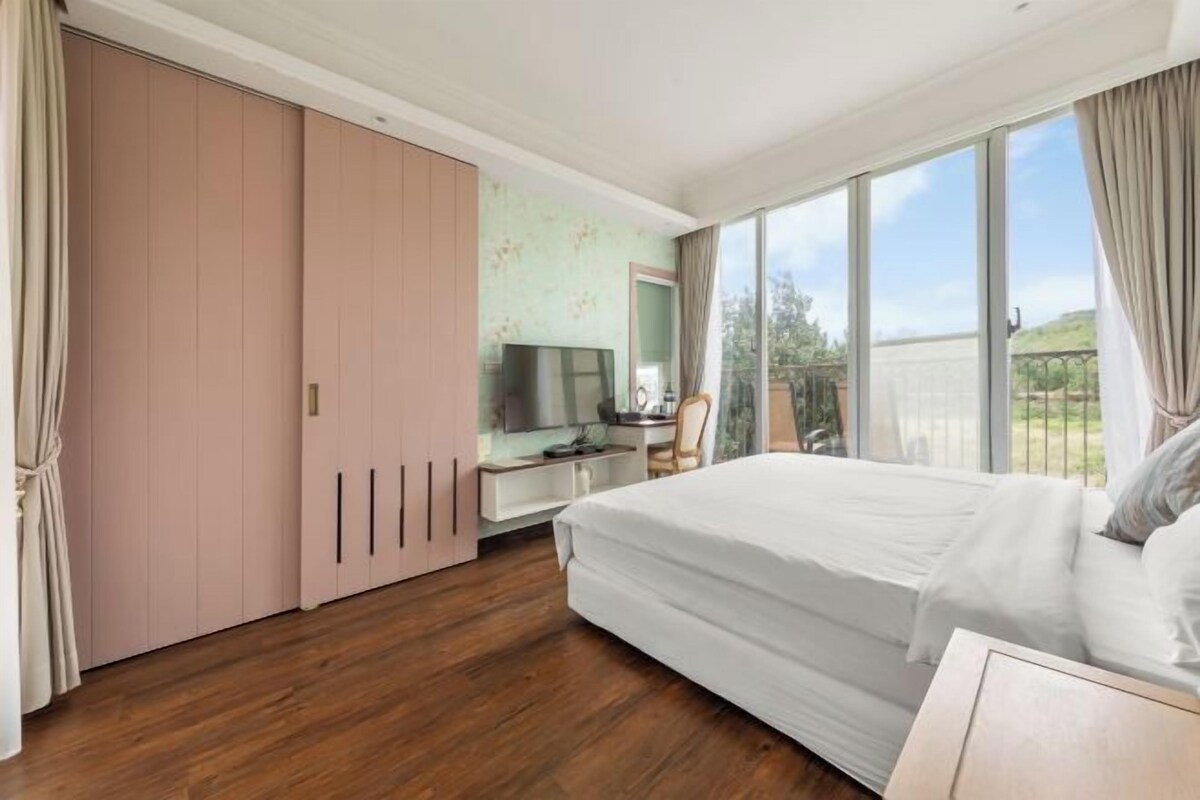 Ein Schlafzimmer mit einem großen Bett, einem Schreibtisch, einem Fernseher und einem Schiebetürenschrank.