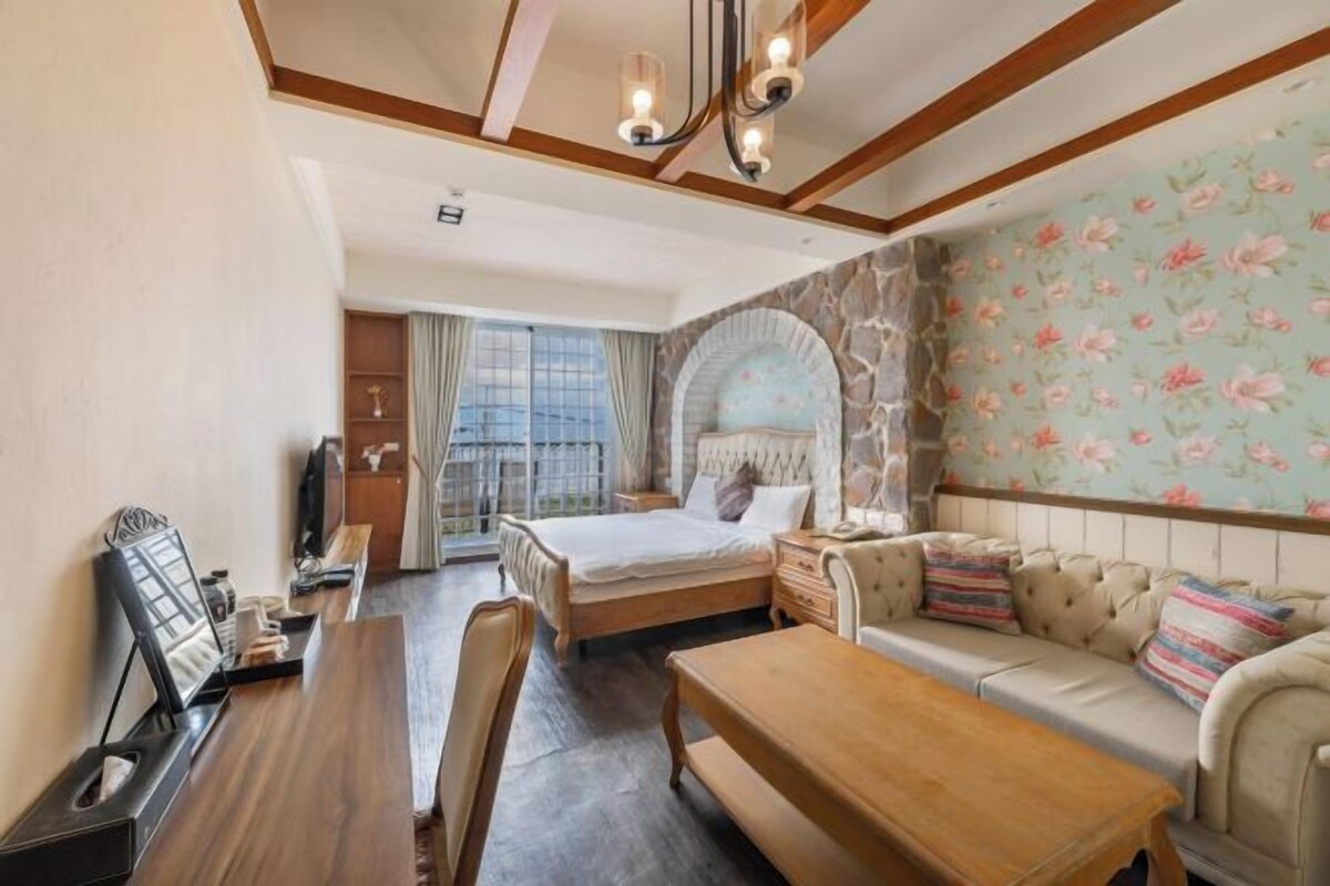 Ein Schlafzimmer mit Bett, Sofa, Holztisch und Fernseher.