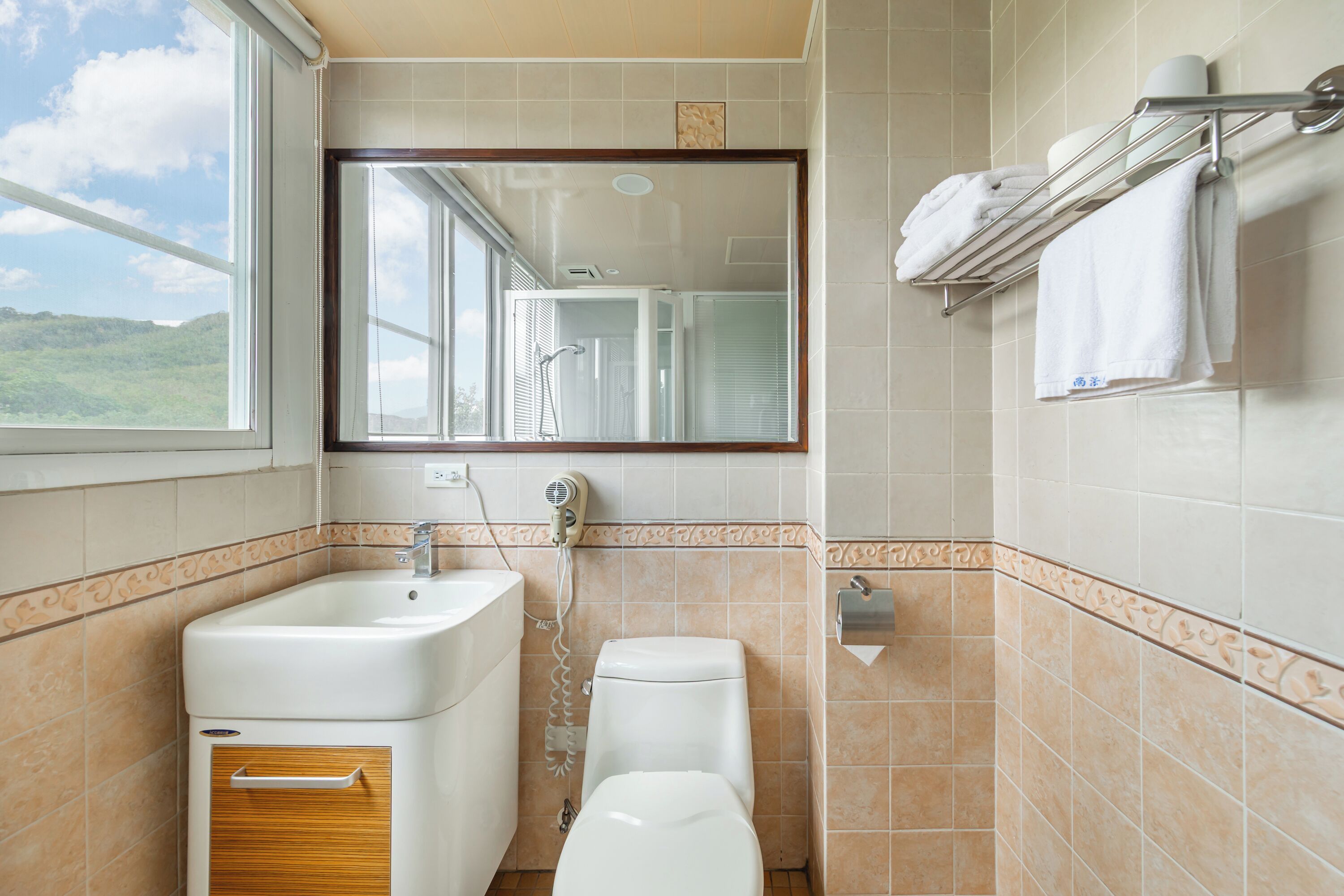 Un baño con lavamanos, inodoro y ventana con vista al exterior.