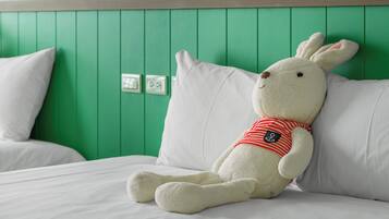 Un conejo de peluche sobre una cama con ropa de cama blanca y paredes verdes.