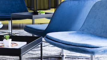 A modern hotel lobby with blue seating, a green table, and a person in the background.