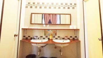 Une salle de bain avec deux lavabos, un miroir et trois poubelles.