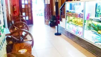 A corridor with a tiled floor, wooden wheelbarrows, a glass display case with items, and a staircase with a railing.