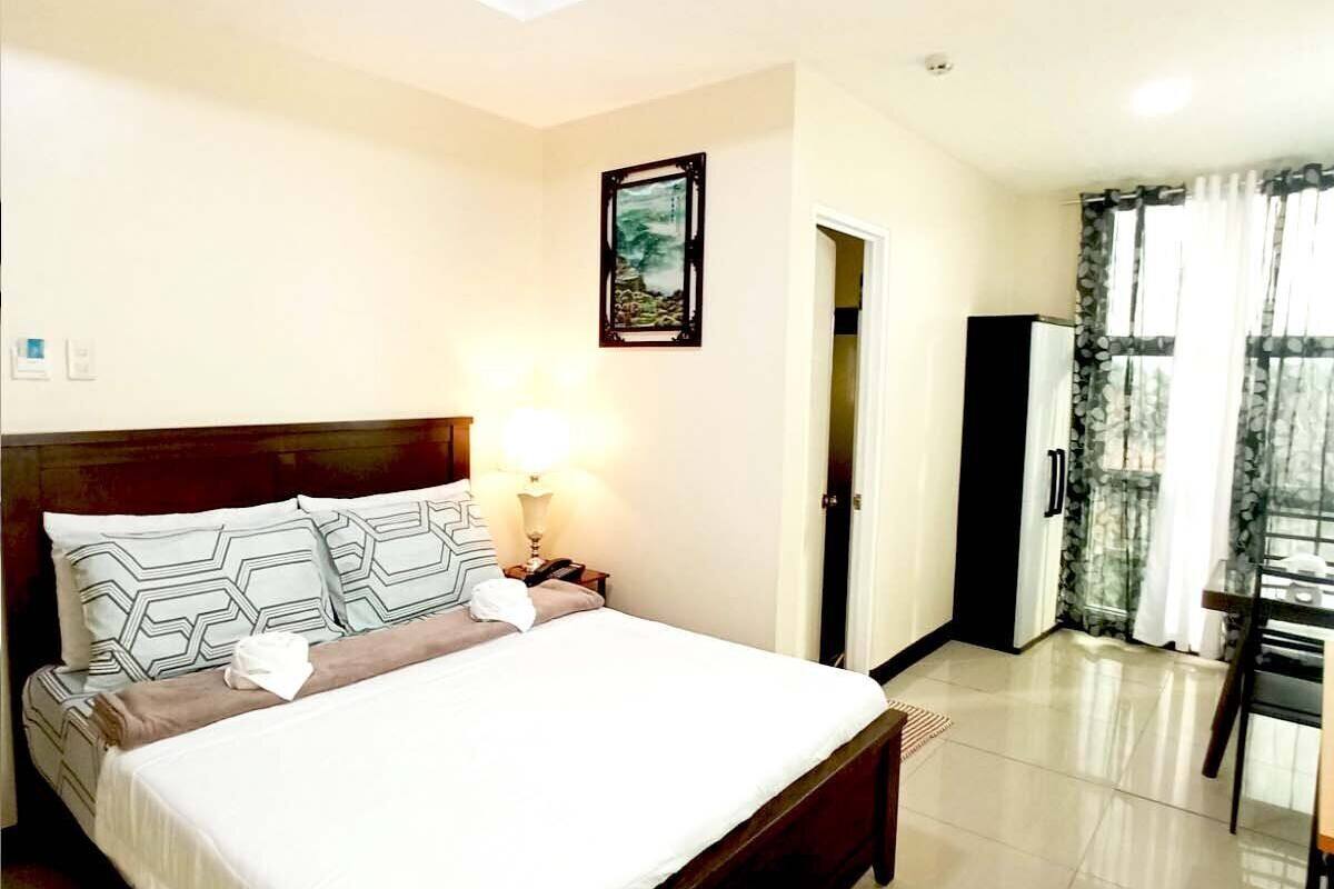 A hotel room with a bed, bedside table, lamp, and a painting on the wall.