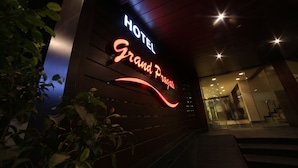 A hotel entrance with a neon sign reading "HOTEL Grand Plaza." - Hotel Grandpragati (Surat)