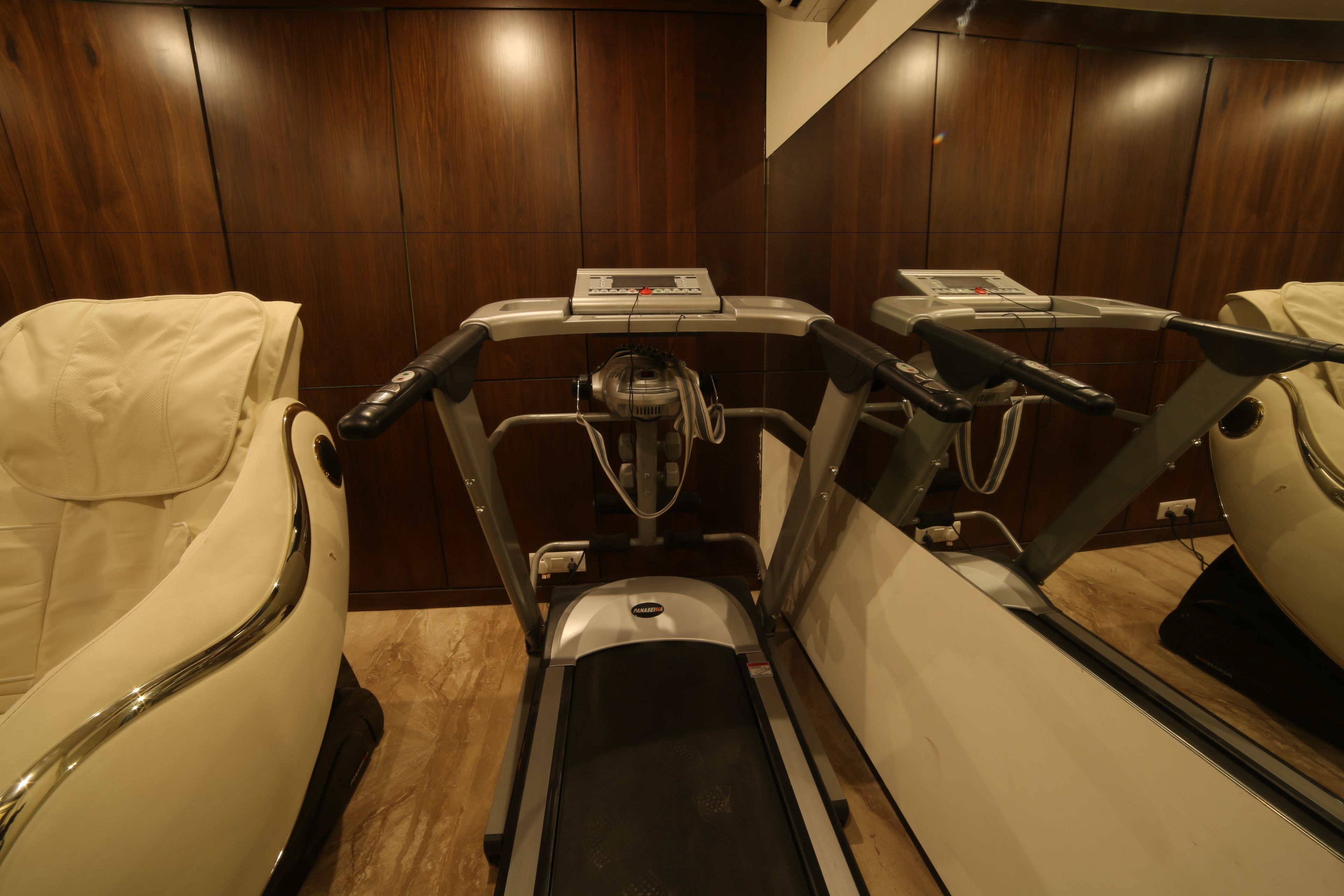 Una habitación con una cinta de correr y una silla de masaje.