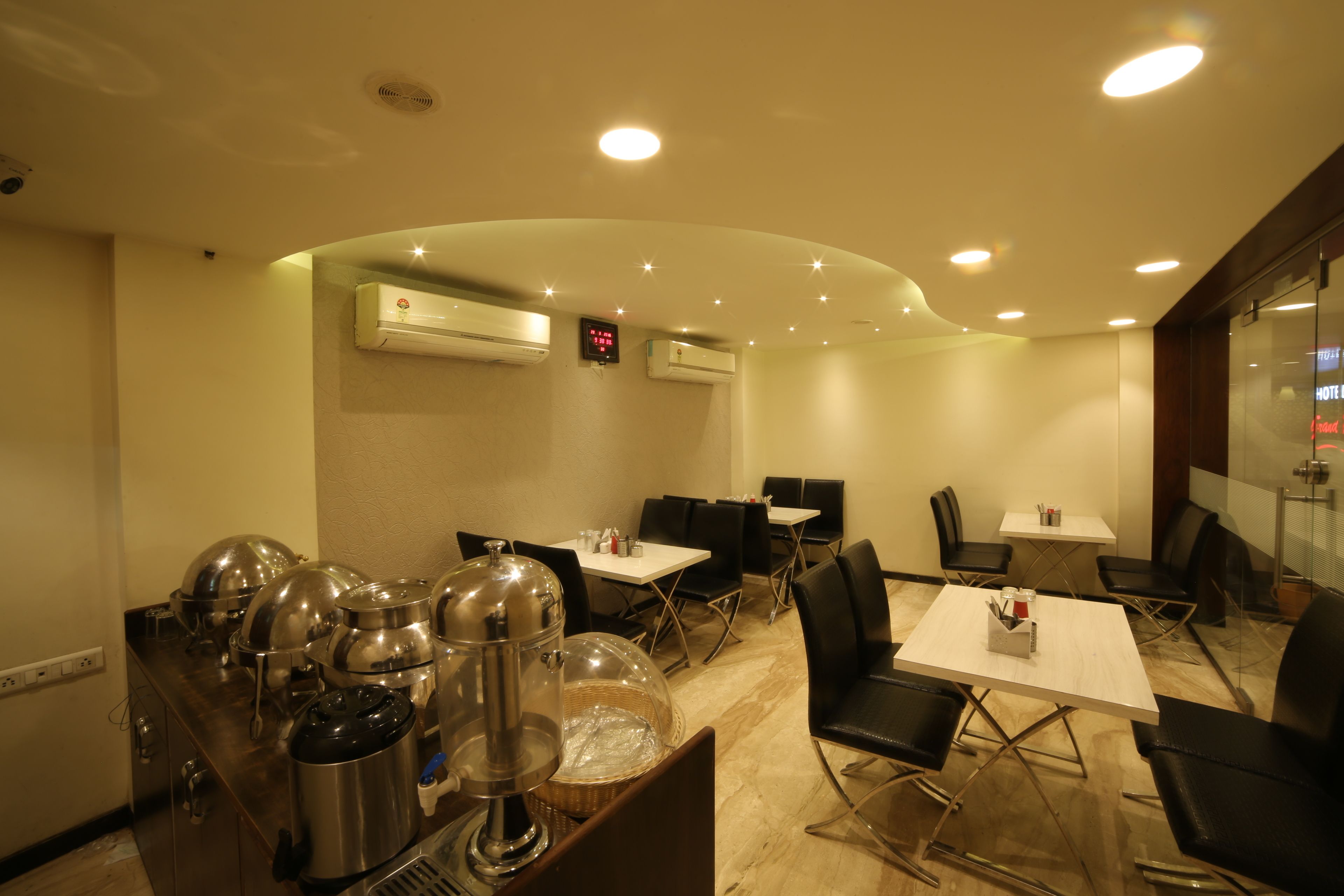 A hotel dining area with tables, chairs, and kitchen equipment.